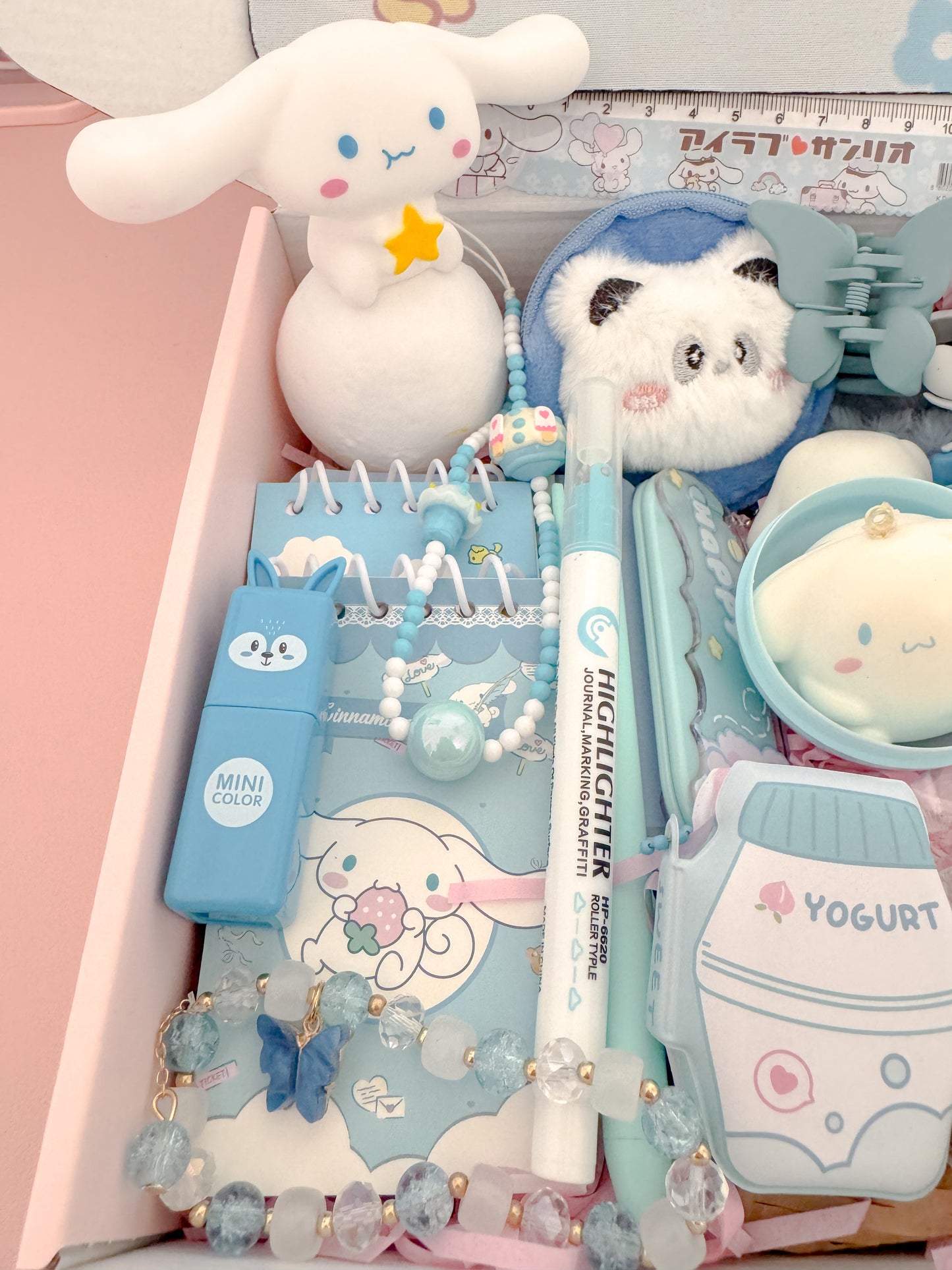 Stationery set with cute animal-themed items including a notebook, pen, and stickers on a pink background.